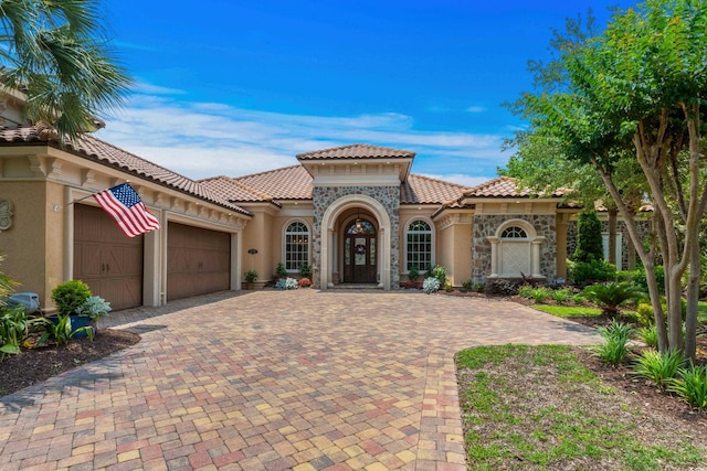 9737 Catalonia Ct, Myrtle Beach, SC 29579 - mediterranean / spanish house with stucco siding, a garage, a tiled roof, decorative driveway, and stone siding
