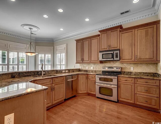 1613 James Island Ave, North Myrtle Beach, SC 29582 - kitchen with appliances with stainless steel finishes, ornamental molding, dark stone countertops, light wood-style flooring, and hanging light fixtures