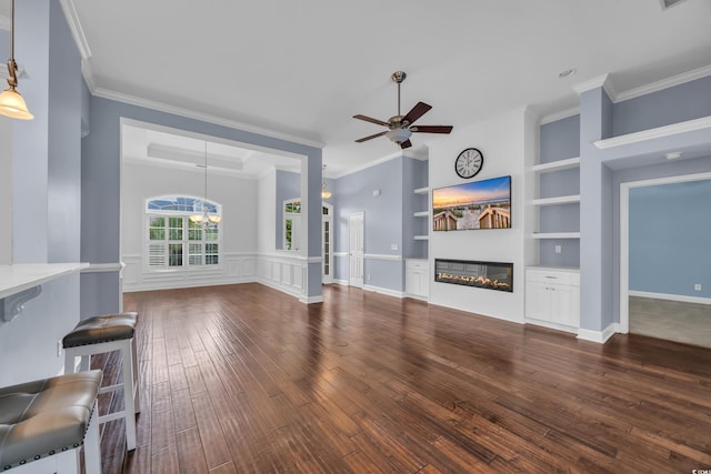 760 Carolina Farms Blvd, Myrtle Beach, SC 29579 - unfurnished living room featuring a glass covered fireplace, built in features, ceiling fan, dark wood-type flooring, and ornamental molding
