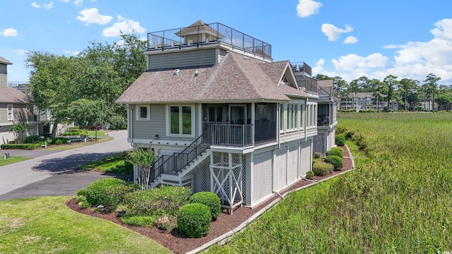 1663 Harbor Dr, North Myrtle Beach, SC 29582 - back of property featuring a shingled roof, stairs, a sunroom, and a lawn