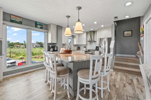 1663 Harbor Dr, North Myrtle Beach, SC 29582 - kitchen with wall chimney range hood, appliances with stainless steel finishes, light stone counters, light wood-style floors, and recessed lighting