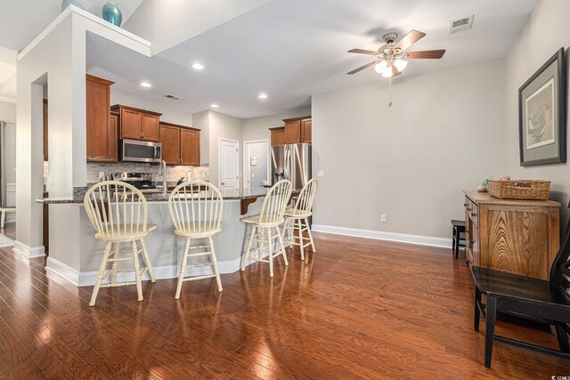 2010 Chattooga Ct, Myrtle Beach, SC 29588 - kitchen with stainless steel appliances, a peninsula, a ceiling fan, brown cabinets, and dark wood finished floors