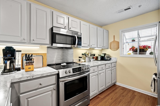 1401 Lighthouse Dr Unit 4334, North Myrtle Beach, SC 29582 - kitchen with appliances with stainless steel finishes, wood finished floors, light countertops, a textured ceiling, and white cabinetry