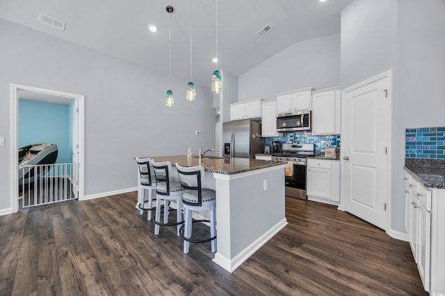 1520 Jardine Loop, Little River, SC 29566 - kitchen featuring stainless steel appliances, decorative backsplash, a breakfast bar area, an island with sink, and white cabinets