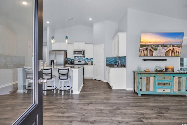 1520 Jardine Loop, Little River, SC 29566 - kitchen featuring stainless steel appliances, a breakfast bar area, white cabinets, decorative backsplash, and dark wood-type flooring