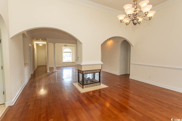 413 Sea Vista Ln, North Myrtle Beach, SC 29582 - unfurnished dining area featuring wood finished floors, a chandelier, crown molding, a multi sided fireplace, and arched walkways