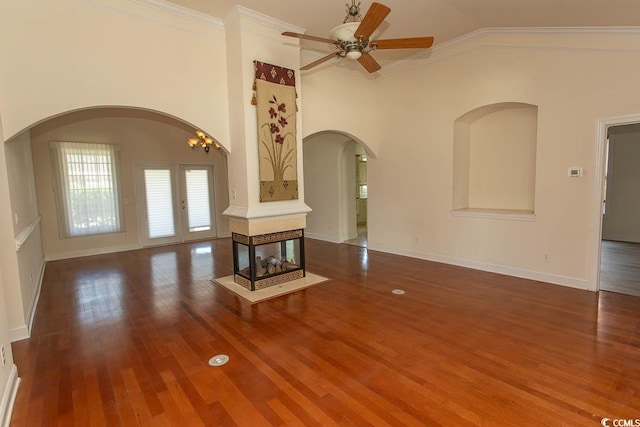 413 Sea Vista Ln, North Myrtle Beach, SC 29582 - unfurnished living room featuring arched walkways, ornamental molding, a ceiling fan, wood finished floors, and vaulted ceiling