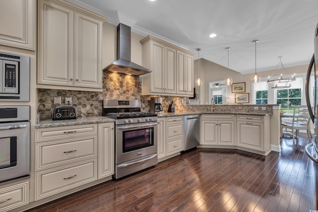 124 Turtle Creek Dr, Pawleys Island, SC 29585 - kitchen with stainless steel appliances, wall chimney range hood, cream cabinetry, a peninsula, and dark wood-style floors