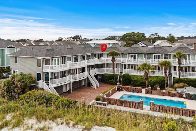 1217 S Ocean Blvd Unit 5, Surfside Beach, SC 29575 - back of house with an outdoor pool, a residential view, roof with shingles, and stairway