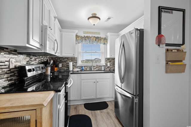 1217 S Ocean Blvd Unit 5, Surfside Beach, SC 29575 - kitchen with stainless steel appliances, decorative backsplash, white cabinetry, light wood finished floors, and dark countertops