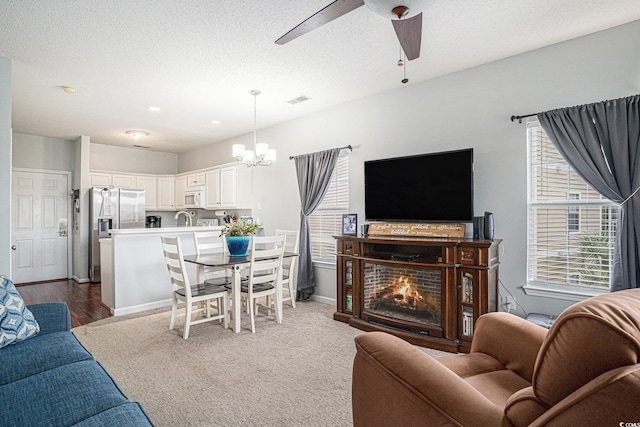 2000 Cross Gate Blvd Unit 202, Surfside Beach, SC 29575 - living room with a ceiling fan, a chandelier, dark carpet, a textured ceiling, and a lit fireplace