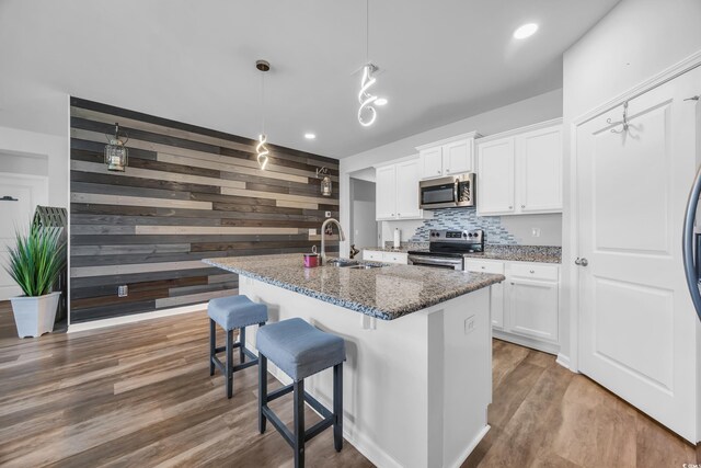 2882 Ophelia Way, Myrtle Beach, SC 29577 - kitchen featuring appliances with stainless steel finishes, wooden walls, white cabinets, light stone countertops, and wood finished floors