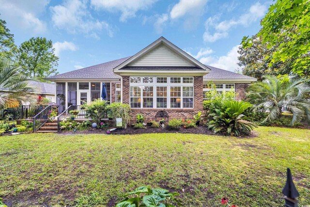 139 Olde Canal Loop, Pawleys Island, SC 29585 - rear view of house featuring a sunroom, brick siding, a yard, and roof with shingles
