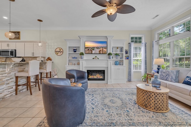 139 Olde Canal Loop, Pawleys Island, SC 29585 - living area with light tile patterned flooring, a glass covered fireplace, a ceiling fan, and crown molding