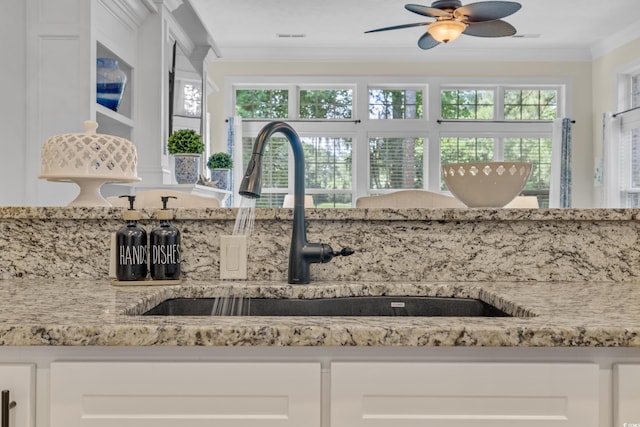 139 Olde Canal Loop, Pawleys Island, SC 29585 - kitchen with white cabinets, light stone counters, ornamental molding, a ceiling fan, and glass insert cabinets