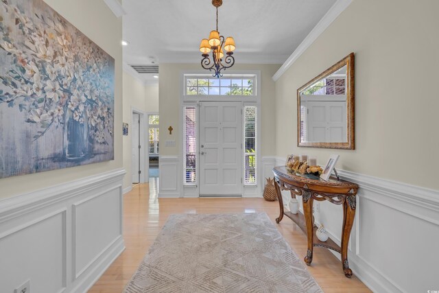 139 Olde Canal Loop, Pawleys Island, SC 29585 - foyer entrance with a chandelier, ornamental molding, a decorative wall, wainscoting, and light wood finished floors