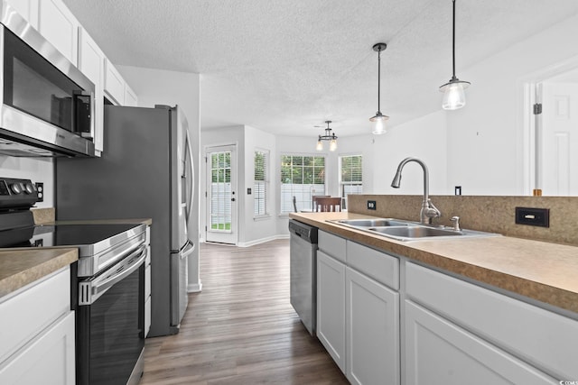 1331 Bermuda Ct, Surfside Beach, SC 29575 - kitchen with appliances with stainless steel finishes, dark wood-style flooring, white cabinetry, hanging light fixtures, and a textured ceiling