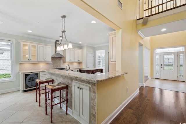 28 Grey Moss Rd, Murrells Inlet, SC 29576 - kitchen featuring wall chimney exhaust hood, beverage cooler, a breakfast bar area, decorative backsplash, and light stone counters