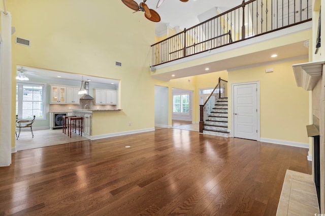 28 Grey Moss Rd, Murrells Inlet, SC 29576 - unfurnished living room featuring a fireplace with flush hearth, ceiling fan, stairway, healthy amount of natural light, and a high ceiling