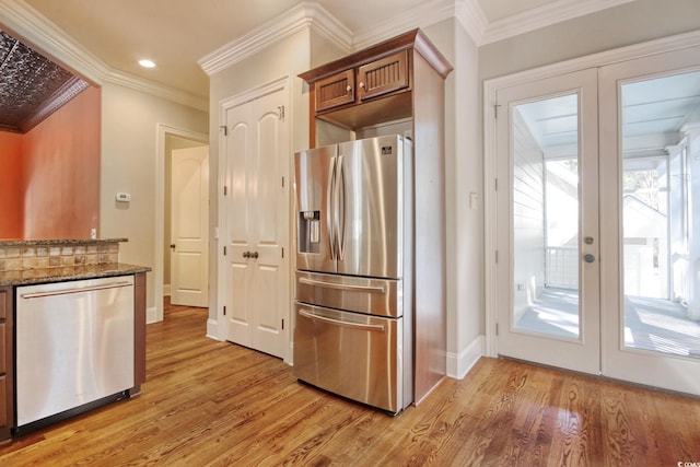 55 Pineberry Dr, Georgetown, SC 29440 - kitchen featuring appliances with stainless steel finishes, light wood finished floors, dark stone counters, french doors, and ornamental molding