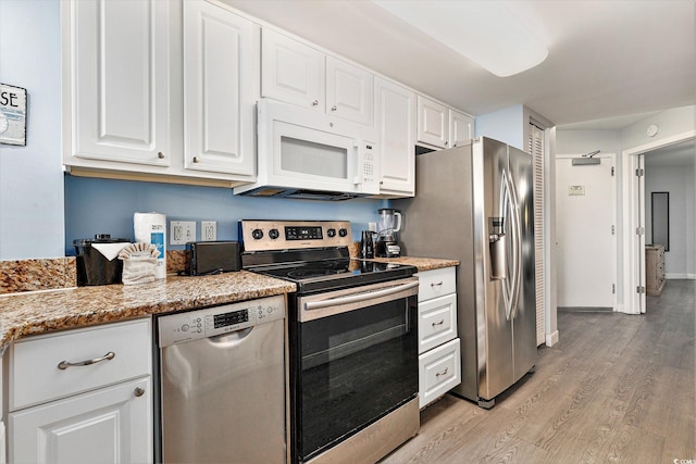 2201 S Ocean Blvd Unit 103, Myrtle Beach, SC 29577 - kitchen with appliances with stainless steel finishes, light wood-type flooring, white cabinetry, and light stone counters