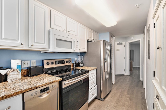 2201 S Ocean Blvd Unit 103, Myrtle Beach, SC 29577 - kitchen with appliances with stainless steel finishes, light wood finished floors, white cabinets, and light stone countertops