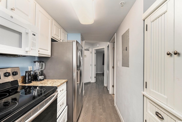 2201 S Ocean Blvd Unit 103, Myrtle Beach, SC 29577 - kitchen featuring stainless steel electric stove, white microwave, light wood-style floors, white cabinets, and electric panel