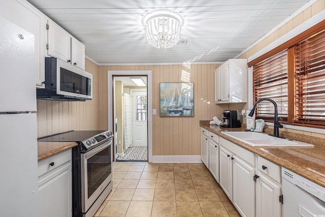 1416 Edge Dr, North Myrtle Beach, SC 29582 - kitchen featuring appliances with stainless steel finishes, white cabinets, a chandelier, wood walls, and light tile patterned floors