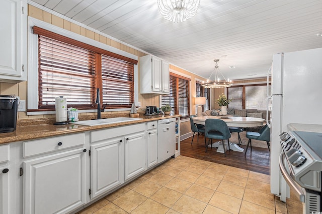 1416 Edge Dr, North Myrtle Beach, SC 29582 - kitchen with a chandelier, stove, dishwashing machine, light tile patterned floors, and white cabinetry