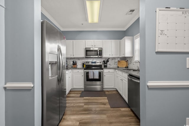 6015 Catalina Dr Unit 932, North Myrtle Beach, SC 29582 - kitchen featuring appliances with stainless steel finishes, white cabinets, wood finished floors, stone countertops, and crown molding