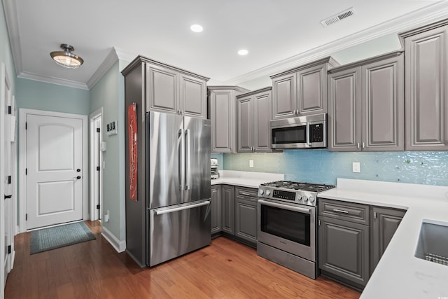 5 Ruth St, Murrells Inlet, SC 29576 - kitchen featuring stainless steel appliances, gray cabinetry, crown molding, light wood-style floors, and tasteful backsplash