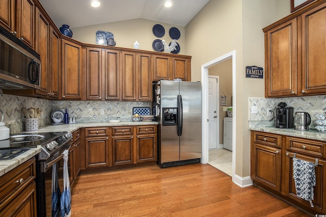 388 Sea Turtle Dr, Myrtle Beach, SC 29588 - kitchen with stainless steel appliances, washer / dryer, light wood-style floors, backsplash, and lofted ceiling