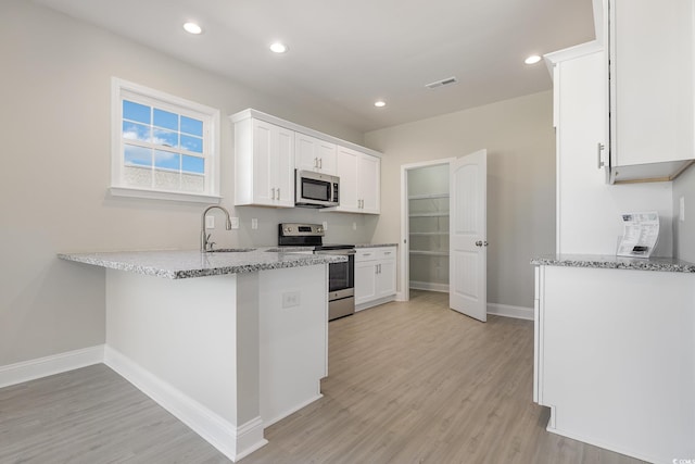 369 Log Cabin Rd, Loris, SC 29569 - kitchen with appliances with stainless steel finishes, light wood-type flooring, light stone counters, white cabinets, and recessed lighting