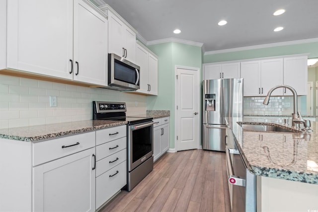 597 Heritage Downs Dr, Conway, SC 29526 - kitchen with stainless steel appliances, ornamental molding, recessed lighting, light wood-style flooring, and white cabinetry