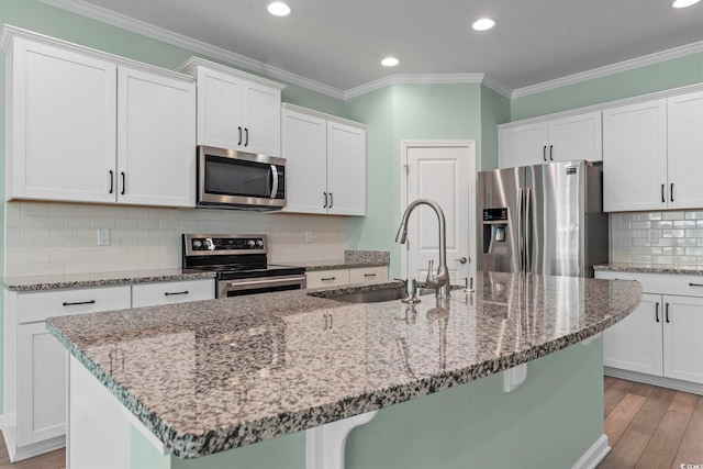 597 Heritage Downs Dr, Conway, SC 29526 - kitchen featuring appliances with stainless steel finishes, an island with sink, light wood-style floors, white cabinets, and ornamental molding