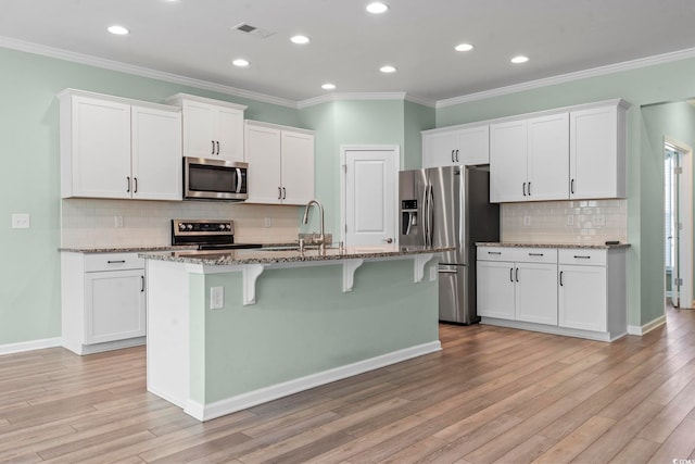 597 Heritage Downs Dr, Conway, SC 29526 - kitchen featuring appliances with stainless steel finishes, a breakfast bar, backsplash, white cabinets, and light stone countertops