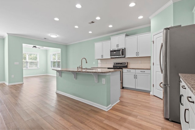 597 Heritage Downs Dr, Conway, SC 29526 - kitchen with stainless steel appliances, ornamental molding, a breakfast bar, light stone countertops, and decorative backsplash