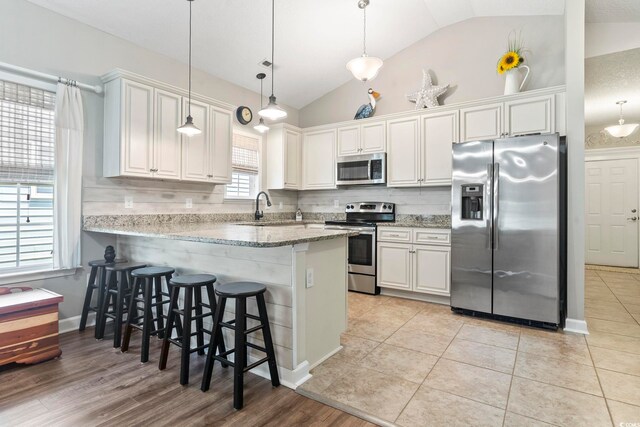 236 Palm Cove Cir, Myrtle Beach, SC 29588 - kitchen featuring stainless steel appliances, vaulted ceiling, a peninsula, a breakfast bar area, and decorative backsplash