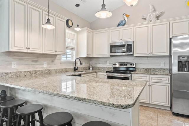 236 Palm Cove Cir, Myrtle Beach, SC 29588 - kitchen featuring appliances with stainless steel finishes, a peninsula, a kitchen bar, light stone countertops, and decorative light fixtures