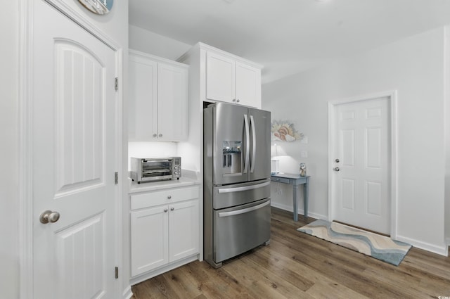 668 Rycola Cir, Surfside Beach, SC 29575 - kitchen with stainless steel refrigerator with ice dispenser, white cabinets, wood finished floors, and light countertops