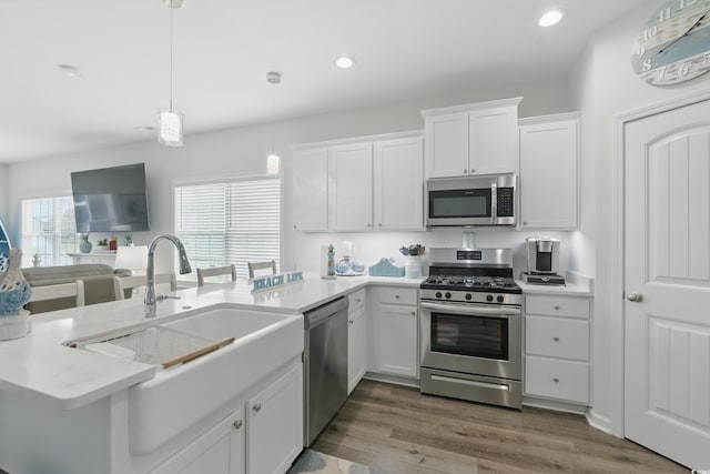 668 Rycola Cir, Surfside Beach, SC 29575 - kitchen with appliances with stainless steel finishes, a peninsula, white cabinetry, wood finished floors, and pendant lighting
