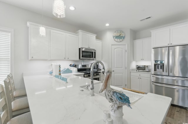 668 Rycola Cir, Surfside Beach, SC 29575 - kitchen featuring stainless steel appliances, white cabinetry, recessed lighting, a kitchen breakfast bar, and hanging light fixtures