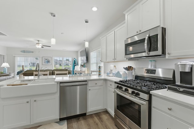 668 Rycola Cir, Surfside Beach, SC 29575 - kitchen featuring appliances with stainless steel finishes, open floor plan, a peninsula, white cabinets, and light wood-style floors