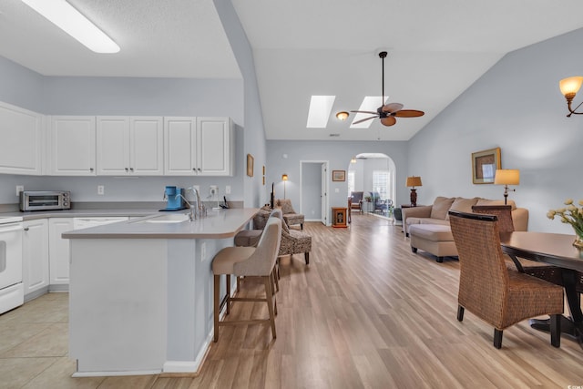 4520 Lighthouse Dr Unit 29B, Little River, SC 29566 - kitchen with arched walkways, a peninsula, white cabinetry, a ceiling fan, and a kitchen breakfast bar