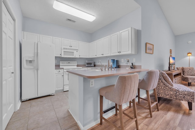 4520 Lighthouse Dr Unit 29B, Little River, SC 29566 - kitchen with white appliances, a breakfast bar, a peninsula, and white cabinetry