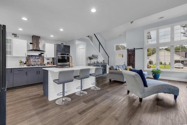 35 Easter Lilly Ct, Murrells Inlet, SC 29576 - kitchen with wall chimney exhaust hood, stainless steel gas stovetop, a breakfast bar area, light countertops, and a barn door