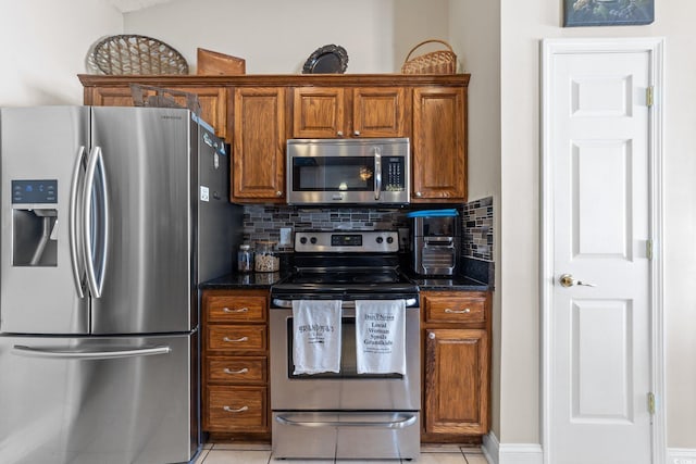 200 Silverbelle Blvd, Longs, SC 29568 - kitchen with stainless steel appliances, brown cabinetry, tasteful backsplash, light tile patterned floors, and dark stone countertops