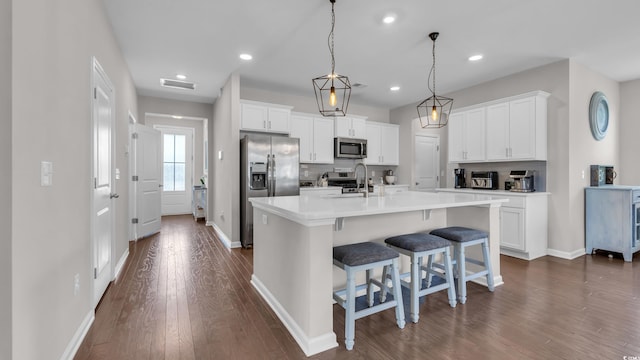 356 Ocean Commons Dr, Surfside Beach, SC 29575 - kitchen featuring stainless steel appliances, dark wood finished floors, a kitchen bar, white cabinetry, and a center island with sink