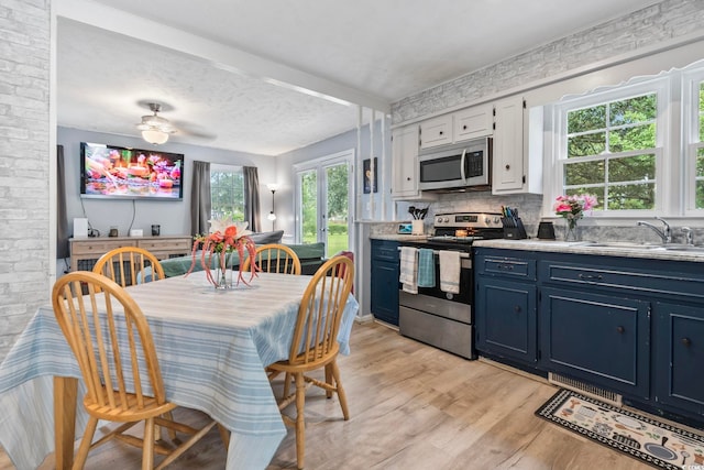 169 Ole Maple St, Loris, SC 29569 - kitchen featuring appliances with stainless steel finishes, blue cabinetry, light wood-style flooring, light countertops, and backsplash