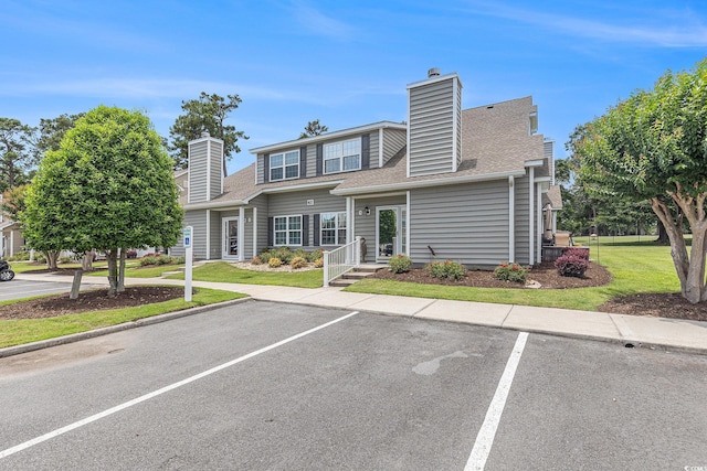 503 N 20th Ave N Unit 41D, North Myrtle Beach, SC 29582 - view of front of home with uncovered parking, a chimney, a shingled roof, and a front yard